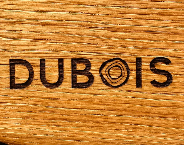 Le nom Dubois marqué au fer dans le fil du chêne.